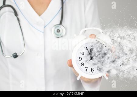 Zeit ist lebensrettend. Konzept Gesundheitswesen. Doktor in weißem Mantel mit Stethoskop, das auf einen auflösenden Wecker zeigt. Die Zeit läuft dem Konzept Stockfoto