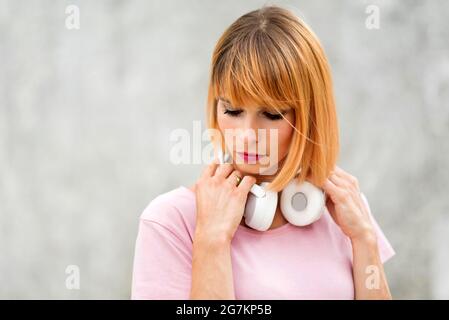 Nahaufnahme einer Frau, die eine wirklich attraktive Frau trägt, die Stereo-Kopfhörer um den Hals trägt und in einem Kopf- und Schulterporträt zur Seite blickt Stockfoto