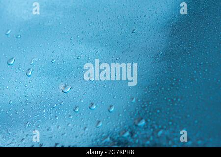Abstrakter Hintergrund mit Regentropfen und schönem blauen Bokeh. Das Konzept des Herbstes und des kalten stürmischen Wetters. Textur von Makrotropfen auf dem verschwommenen Stockfoto
