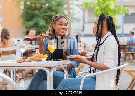 afroamerikanische Frauen genießen Speisen und Getränke auf einer Terrasse im Freien Stockfoto