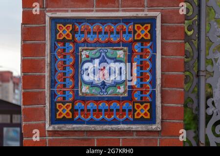 Fragment der Dekoration der Fassade eines alten Gebäudes in Form von Keramikfliesen mit einem floralen Muster Stockfoto