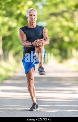 Fit männlichen Rentner streckt sein Bein vor ihm während des Workouts Aufwärmen. Stockfoto