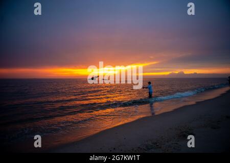 Cape May Point, Usa. Juli 2021. Ein Mann wirft seinen Angelstock am Sunset Beach ins Wasser, während die Sonne über dem versunkenen Schiff SS Atlantus am Mittwoch, den 14. Juli 2021 untergeht, als die Sonne über Sunset Beach in Cape May Point, New Jersey, untergeht. Es wird erwartet, dass die Temperaturen in der Region Philadelphia in den 90er Jahren für die nächsten Tage bleiben werden. ( Kredit: William Thomas Cain/Alamy Live News Stockfoto
