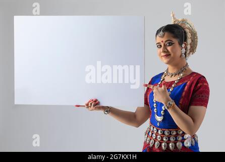 Odissi-Tänzerin zeigt auf ein leeres Plakat Stockfoto