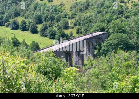 Radfahrer und Wanderer überqueren den Grabstein-Viadukt (Monsal Viaduct), einen Teil des Monsal Trail, von Monsal Head aus gesehen, in der Nähe von Bakewell, Derbyshire, England, Großbritannien Stockfoto