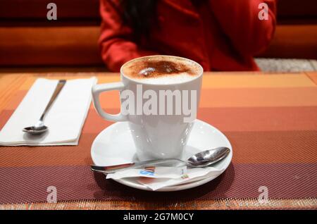Heiße Schokolade mit Milchschaum und Kakaopulver in einer hohen Tasse in einem lokalen Restaurant. Stockfoto