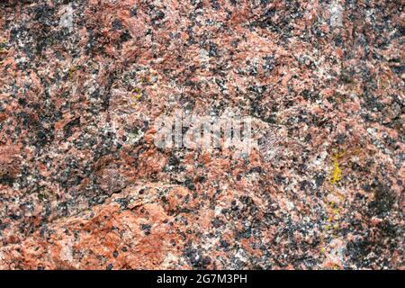 Die Textur von Granit. Der Hintergrundstein. Details aus rotem Granit in der Wand. Stockfoto