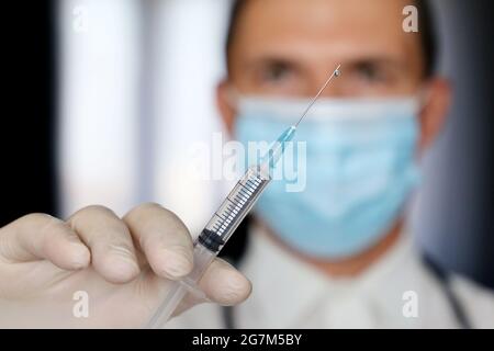 Arzt mit Spritze in der Hand, Mann in medizinischer Maske Vorbereitung auf die Injektion. Konzept der Impfung während einer Covid-19-Pandemie Stockfoto