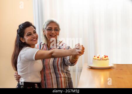 EINE TOCHTER UND MUTTER GENIESSEN UND TANZEN ZUSAMMEN, WÄHREND SIE GEBURTSTAG FEIERN Stockfoto