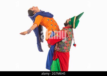 Eine Bhangra-Tänzerin, die eine Giddha-Tänzerin hebt, die einen Tanzschritt darstellt. Stockfoto