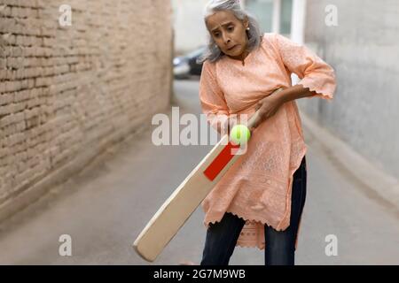 Eine alte Frau spielt Cricket. Stockfoto