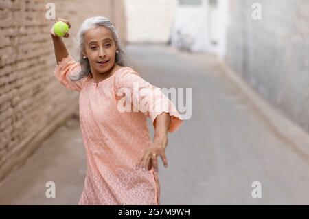 Eine alte Frau spielt Cricket Bowling. Stockfoto