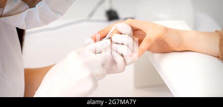 Nahaufnahme von Maniküre Meister mit Maniküre Nipper schneidet Nagelhaut der weiblichen Nägel im Schönheitssalon Stockfoto