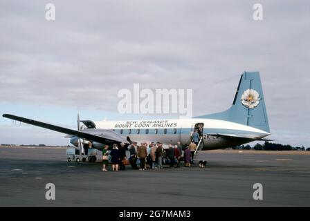 Ein Passagierflugzeug der neuseeländischen Mount Cook Airlines mit Passagieren, die 1969 auf der Asphaltbahn am Flughafen Christchurch einsteigen. Mount Cook Airline war eine regionale Fluggesellschaft, die 1920 gegründet wurde und ihren Sitz in Christchurch, Neuseeland, hatte. Früher Teil der Mount Cook Group und zuletzt eine Tochtergesellschaft von Air New Zealand, wurde der Markenname 2019 mit allen Services unter dem Banner von Air New Zealand außer Betrieb genommen. Das Flugzeug ist ein Hawker Siddeley HS 748, ein mittelgroßes Turboprop-Flugzeug. Auf dem Schwanz ist ein Bild der Mount Cook Lilie, der größten Butterblume der Welt – ein Vintage-Foto aus den 1960er Jahren. Stockfoto