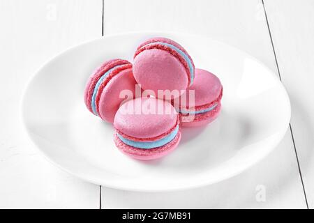 Beerenrosa Makronen mit blau-cremiger Füllung auf dem Teller Stockfoto