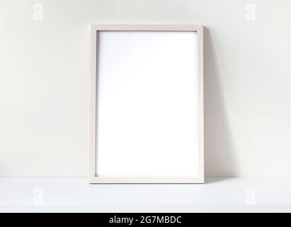 Fotorahmen-Modell mit weißem leeren Blatt auf einem weißen Schreibtisch. Nachbau aus Kiefernholz. Platz für Text. Stockfoto