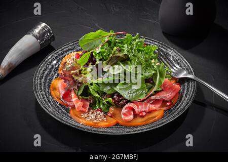 Salat aus Gemüse, Kaki und gesalzenem Lachs mit Granatapfel und Walnüssen Stockfoto