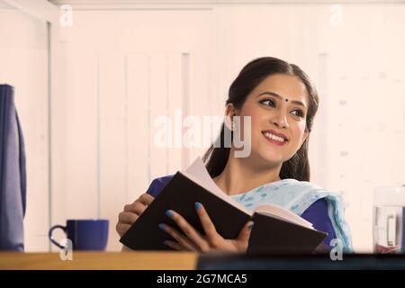 Eine Frau mit einem Buch in der Hand lächelnd. Stockfoto