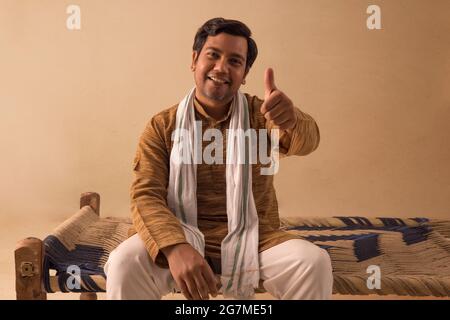 EIN MANN AUS DEM LÄNDLICHEN RAUM ZEIGT GLÜCKLICH DEN DAUMEN VOR DER KAMERA Stockfoto