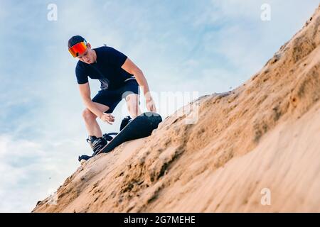 Extremer Absand auf Snowboard in der Wüste. Männlicher Snowboarder auf Dünen. Stockfoto