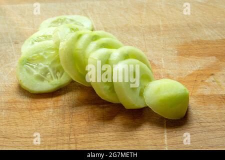 Geschälte und in Scheiben geschnittene Gurken auf einem Holzbrett, aus nächster Nähe Stockfoto