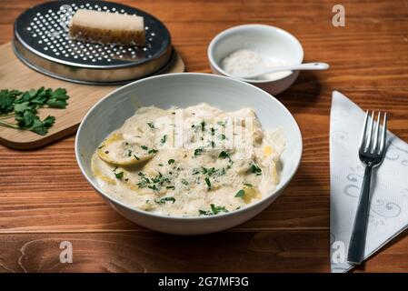 Ravioli mit Pilzen, Parmigiano, Petersilie und frischem Basilikum. Holztisch-Anordnung. Nahaufnahme Stockfoto