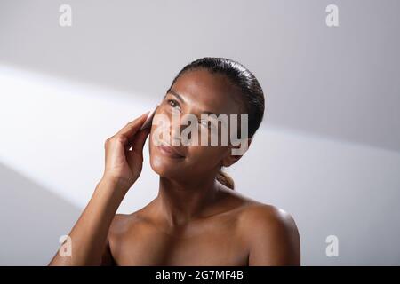 Schönheitsbilder einer Frau mit dunklerem Hautton. Kopf- und Schulterbilder einer zufriedenen, glücklichen Dame mit Baumwoll-Gesichtspads. Stockfoto