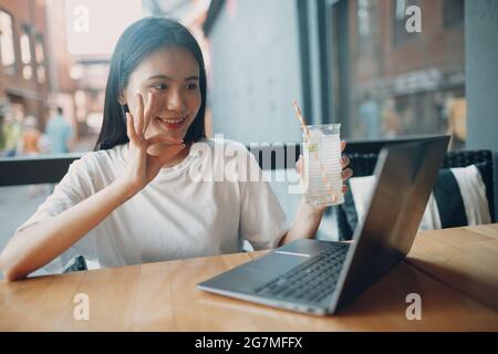 Porträt der asiatischen Frau Student ok Zeichen Hand an Kamera des Laptops sitzen im Café im Freien. Stockfoto