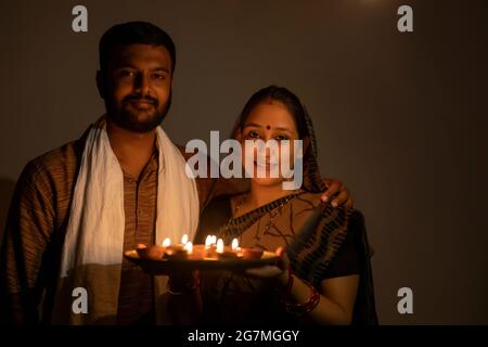 PORTRÄT EINES LANDMANNES UND EINER FRAU, DIE MIT DIYAS IN DER HAND LÄCHELN Stockfoto