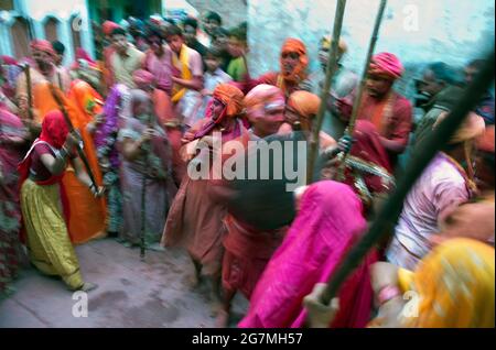 Männer von Barsan überfallen die Nachbarstadt Nandgaon und werden von Nandgaons Frauen mit großen Stöcken geschlagen und mit Holi-farbigen Pulvern beschmiert Stockfoto