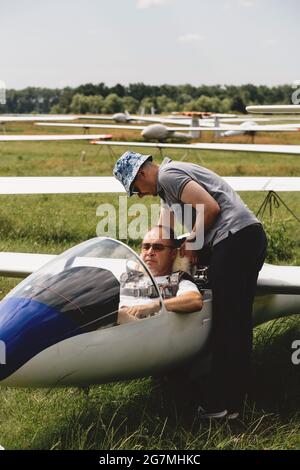 Der Segelflieger bereitet sich auf den Flug mit motorlosen Festflügelflugzeugen vor. Kleine Luftfahrt Extremsport Freizeitbeschäftigung. Mann in der Nähe des Flugzeugs Stockfoto