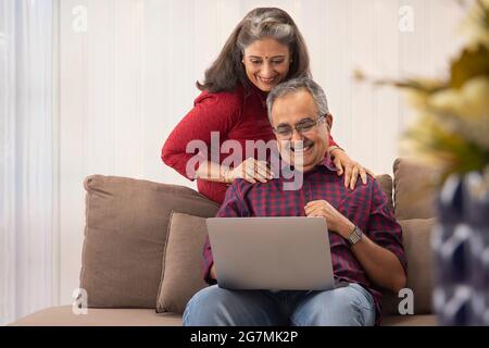 EIN MANN UND EINE FRAU NUTZEN GERNE EINEN LAPTOP FÜR VIDEOANRUFE Stockfoto