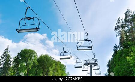 Skilift im Sommer. Sessellift mit leeren Kabinen an einem sonnigen Sommertag gegen den blauen Himmel. Stockfoto