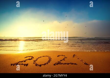 Happy New Year 2021 Konzept, Schriftzug am Strand. Geschriebener Text am Strand bei Sonnenaufgang. Stockfoto