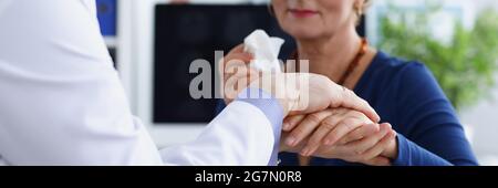 Der Arzt hält die Hand eines älteren Patienten wohlwollend Stockfoto