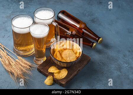 Bier, Chips und Weizenspikelets auf dunkelblauem Hintergrund. Stockfoto