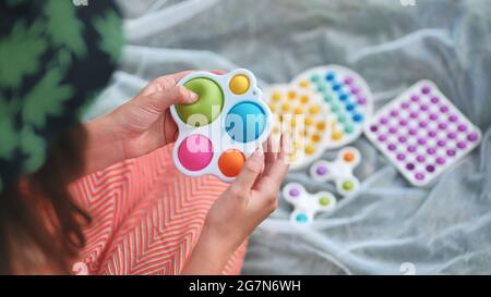 Teenager Mädchen spielt mit Anti-Stress mehrfarbigen Spielzeug popit und einfache Grübchen im Park an einem Sommertag. Stockfoto