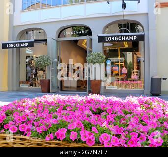 Longchamp Shop Front am Las Rozas Outlet Shopping mit einem Blumenbeet aus rosa Petunien im Sommernachmittag Sonnenlicht Madrid Spanien Stockfoto