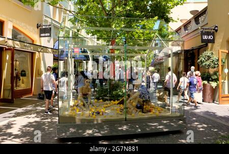 Plexiglas umschlossene Strandszene mit Schaufensterpuppen und Zitronen in Las Rozas Open Air Outlet Shopping Mall Madrid Spain Summer Stockfoto
