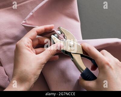 Setzen Sie einen Snap in rosa französisch Frottee mit einem Piercing Nieten Werkzeug. Schnappzange Stockfoto