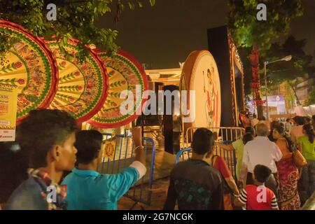 KOLKATA , INDIEN - 28. SEPTEMBER 2017 : Nachtbild der Besucher außerhalb dekorierten Durga Puja Pandal mit alten bengalischen Haus außen Designs mit großem Fan Stockfoto