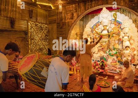 KOLKATA , INDIEN - 27. SEPTEMBER 2017 : Hindu-Priester verehrt Göttin Durga, während Dhaakis (Trommler) in seinem Rücken auftreten. Durga Puja Festival Stockfoto