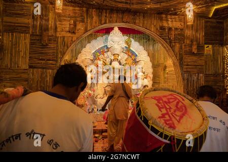 KOLKATA , INDIEN - 27. SEPTEMBER 2017 : Hindu-Priester verehrt Göttin Durga, während Dhaakis (Trommler) in seinem Rücken auftreten. Durga Puja Festival Stockfoto
