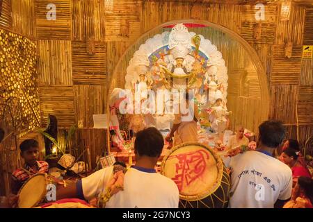 KOLKATA , INDIEN - 27. SEPTEMBER 2017 : Hindu-Priester verehrt Göttin Durga, während Dhaakis (Trommler) in seinem Rücken auftreten. Durga Puja Festival Stockfoto