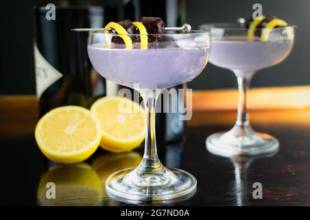 Aviation Gin-Cocktails garniert mit Luxardo-Kirschen: Gin-Cocktails mit Creme de violette, serviert in Coupé-Gläsern Stockfoto