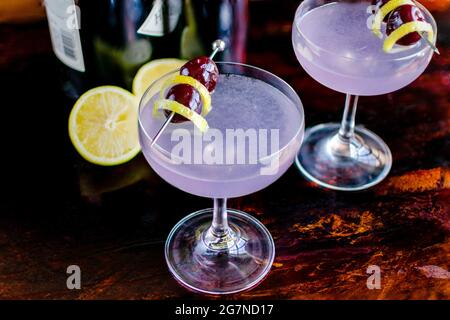 Aviation Gin-Cocktails garniert mit Luxardo-Kirschen: Gin-Cocktails mit Creme de violette, serviert in Coupé-Gläsern Stockfoto