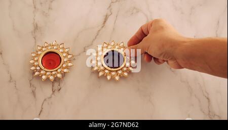 Nahaufnahme einer Hand, die dekorative Diwali-Kerzen anzündet Stockfoto