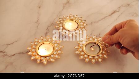 Nahaufnahme einer Hand, die dekorative Diwali-Kerzen anzündet Stockfoto
