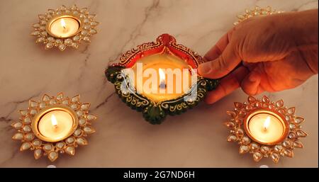 Nahaufnahme einer Hand, die dekorative Diwali-Kerzen anzündet Stockfoto