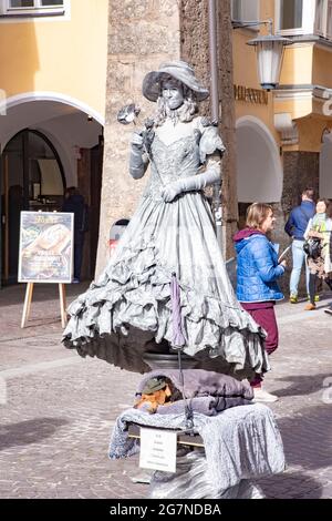 Ein Straßenkünstler in silbernem Metallic-Gewand, der als lebende Statue auf der zentralen Straße der Altstadt von Innsbruck posiert. Aufgenommen in Innsbruck, Österreich Stockfoto